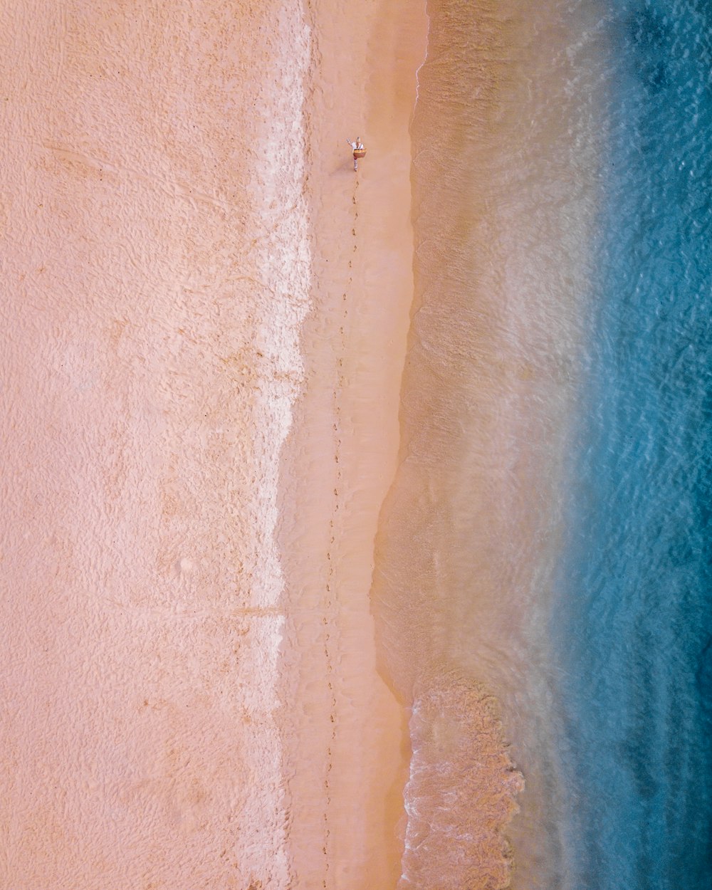 personne marchant sur le sable près du bord de mer laissant des sentiers pédestres