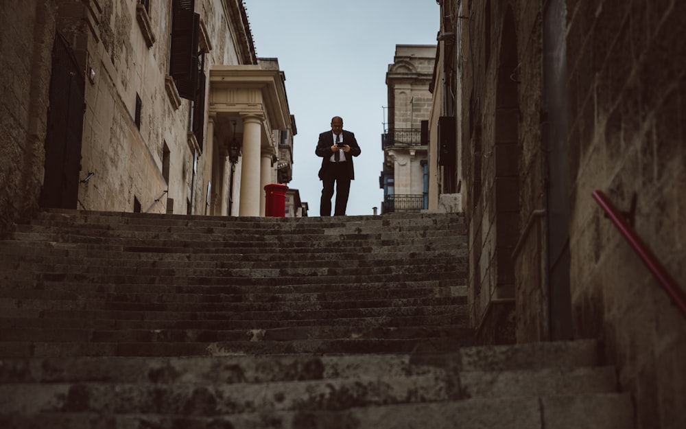 man walking downstairs between concrete buildings