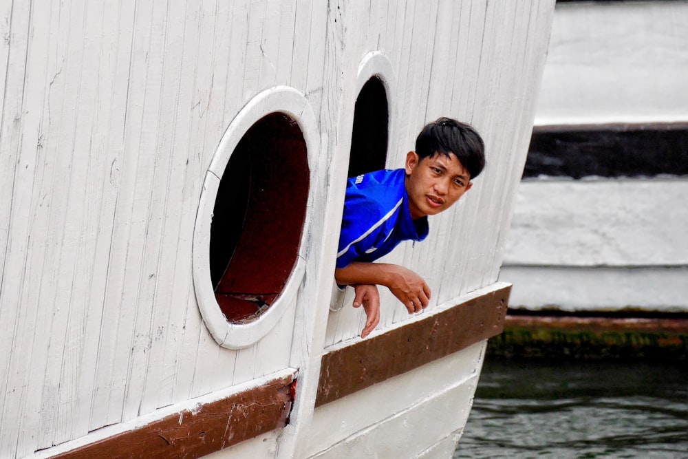 man looking out boat window during daytime