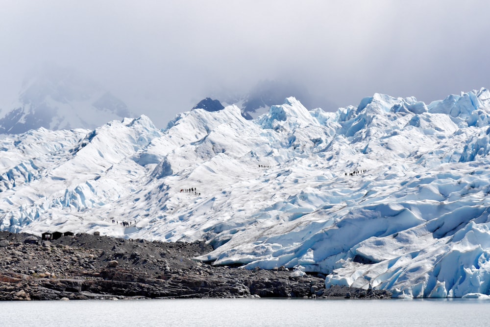 body of water with background of mountain covered with snow