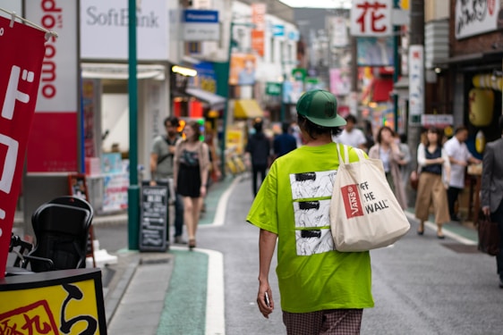 A vibrant city street scene with a person wearing a stylish hoodie and tote bag from Expresion Design and Custom.