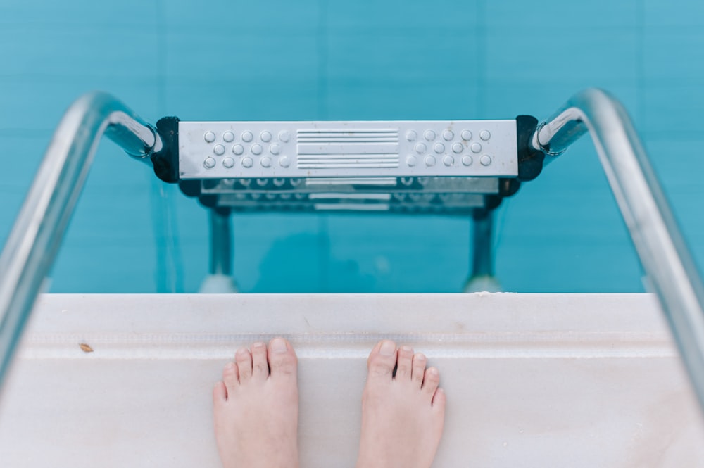 person standing on swimming pool ladder