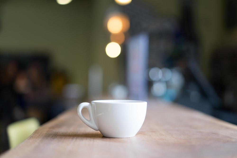 Fotografia bokeh da caneca branca na mesa marrom