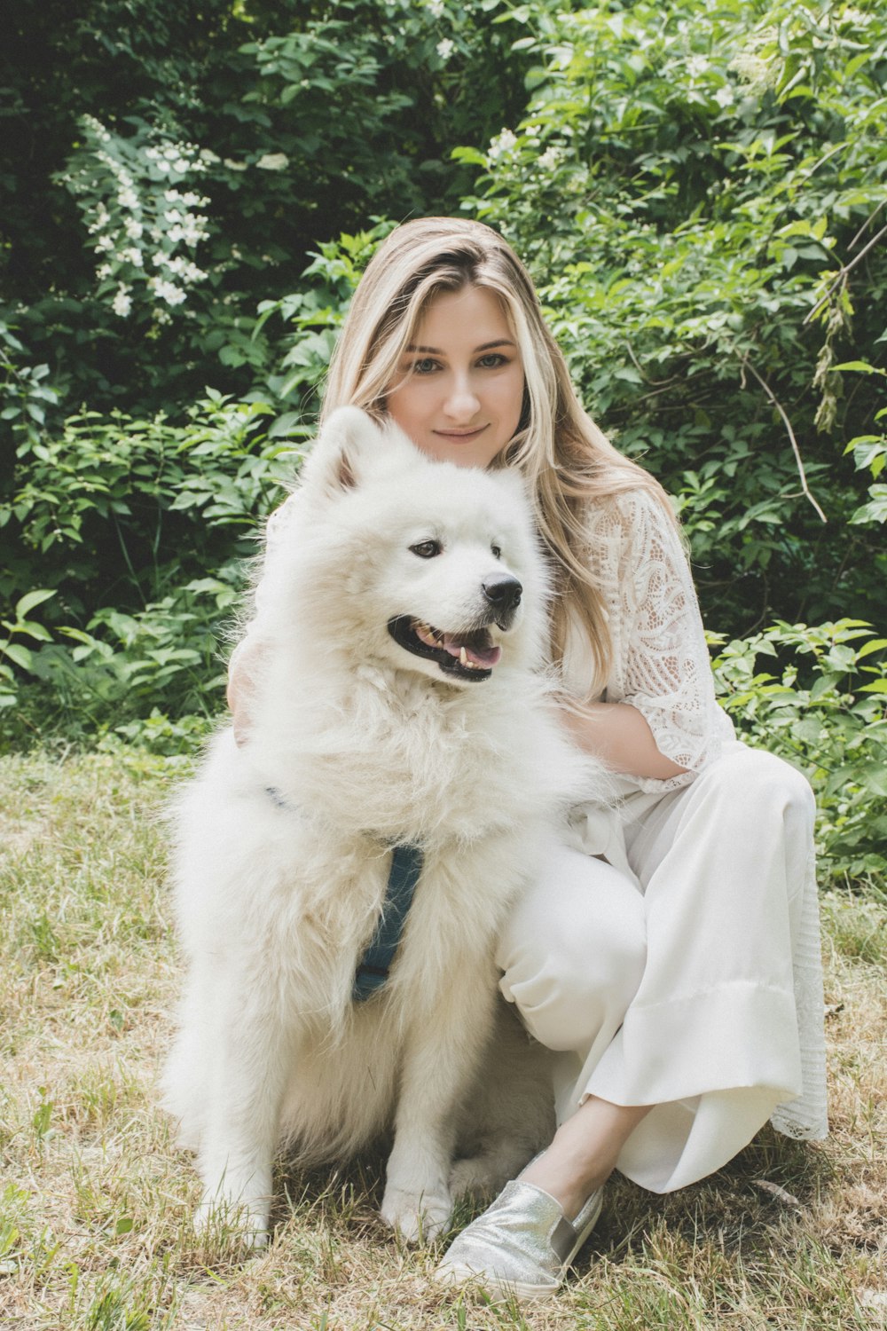 woman sitting on the ground petting white dog