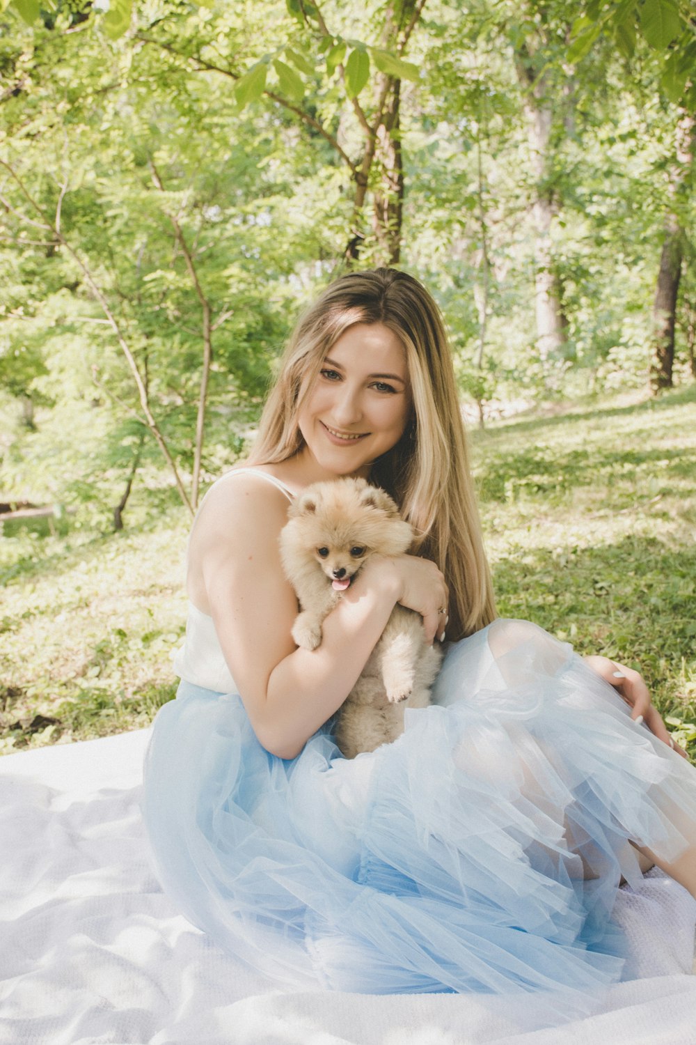 woman sitting on white picnic mat while holding dog