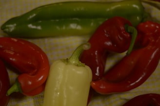 A colorful assortment of fresh peppers including green, red, and yellow varieties displayed on a rustic wooden table.