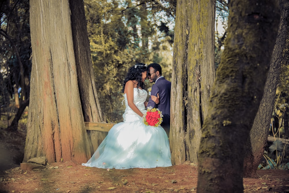 man and woman sitting on wood trunk