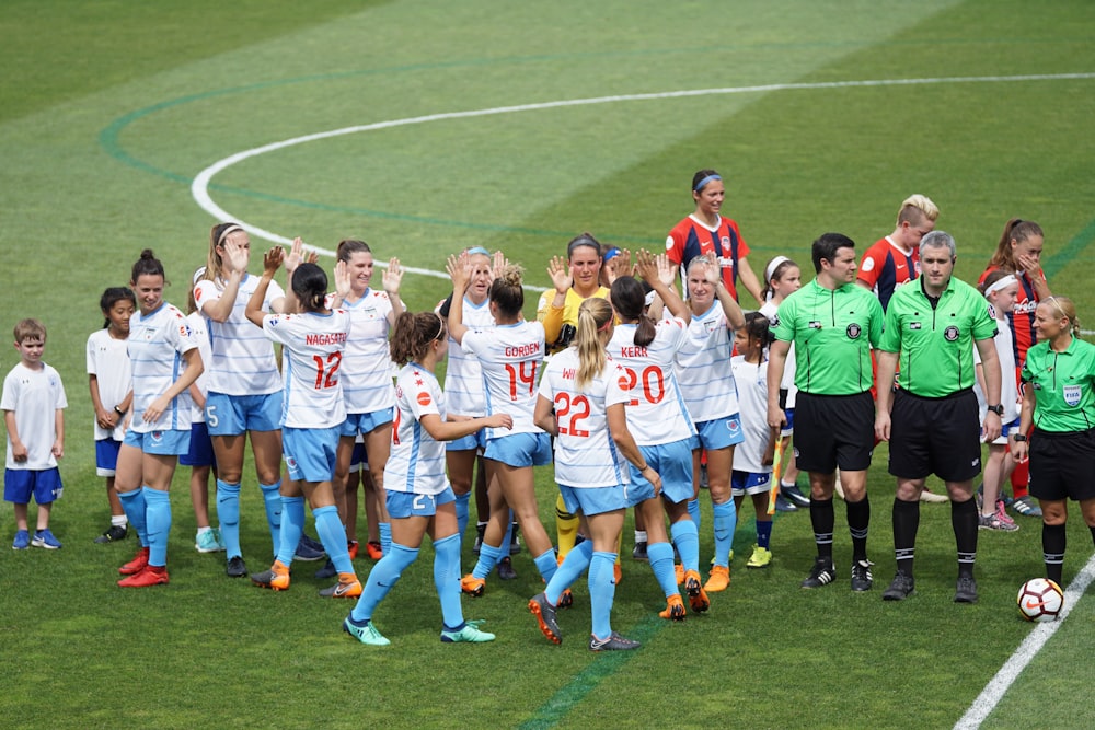 Équipe féminine de soccer debout sur le terrain avec des officiels et des enfants