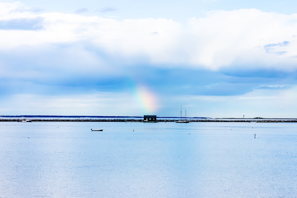 aerial view photography of body of water under cloudy sky with rainbow