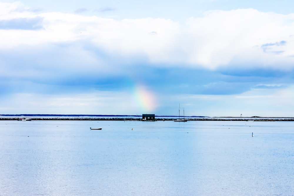 Fotografia aerea dello specchio d'acqua sotto il cielo nuvoloso con l'arcobaleno