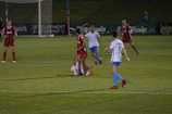 Dynamic shot of players mid-action during an intense futsal match under bright urban lights.