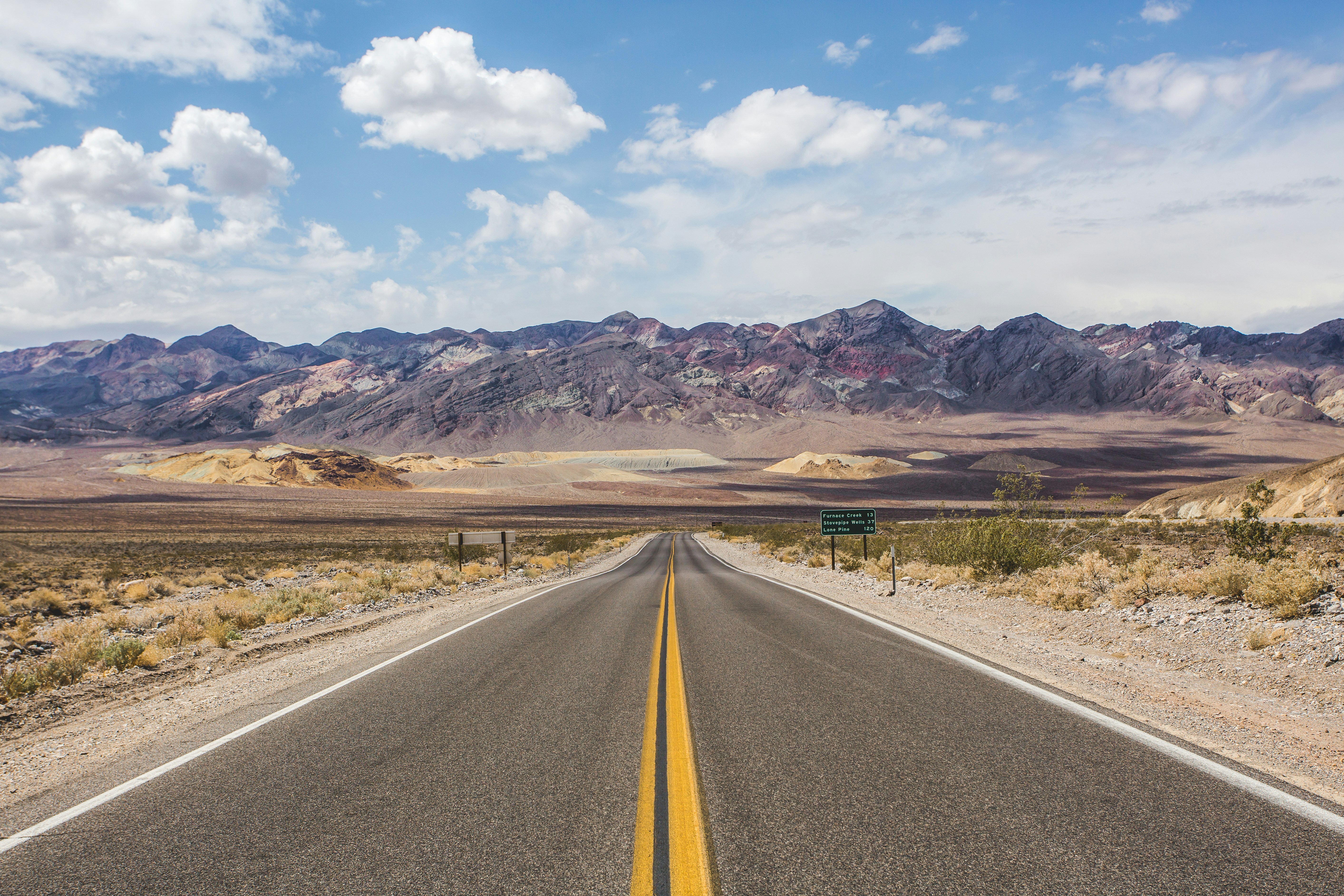 Scenic view of Death Valley National Park's iconic highway stretching into the horizon, surrounded by vast desert landscapes, ideal for exploring in a rented RV