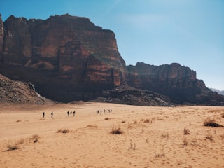 A group of people exploring a desert landscape with mountains in the background.