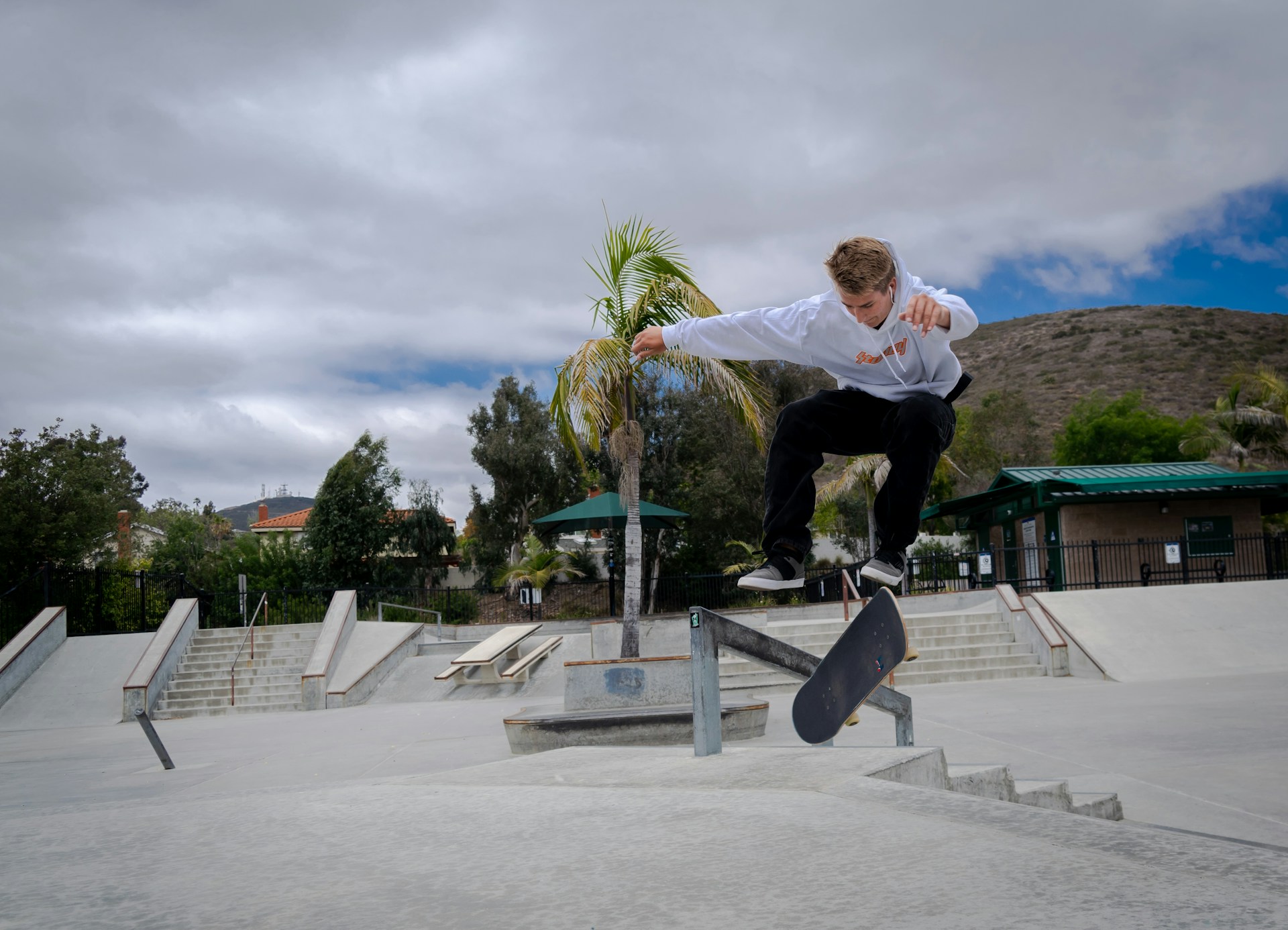 An action shot of a skateboarder performing tricks in a modern skate park, dressed in trendy joggers and a hoodie.
