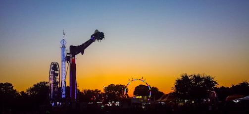 A large, thrilling amusement park ride with colorful lights at dusk.