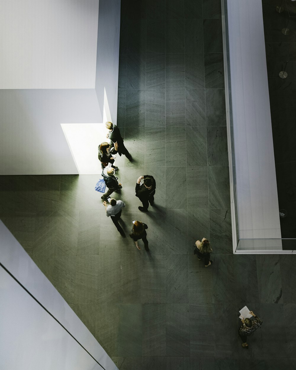 Fotografía aérea de personas de pie y caminando frente a un edificio de concreto blanco