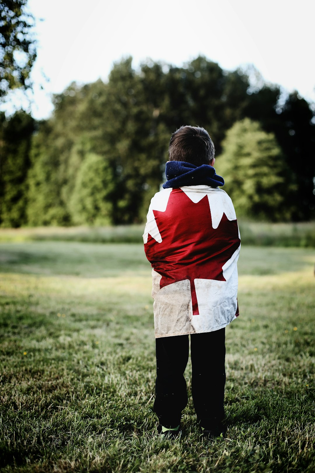 Young boy wearing a garment with a Canadian flag on it.  WHY?  
