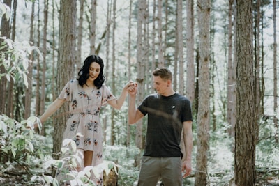 Cinematic shot of a couple walking hand in hand through a softly lit forest.