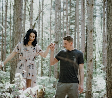 man holding hands with woman near trees