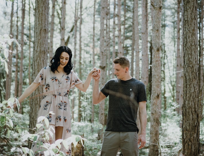 man holding hands with woman near trees