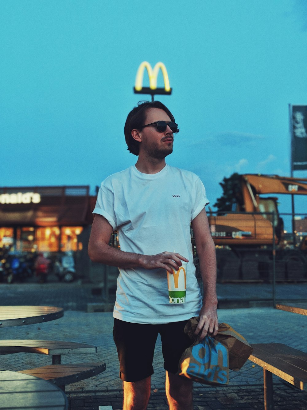 hombre sosteniendo una taza de McDonald al lado de la mesa de camping