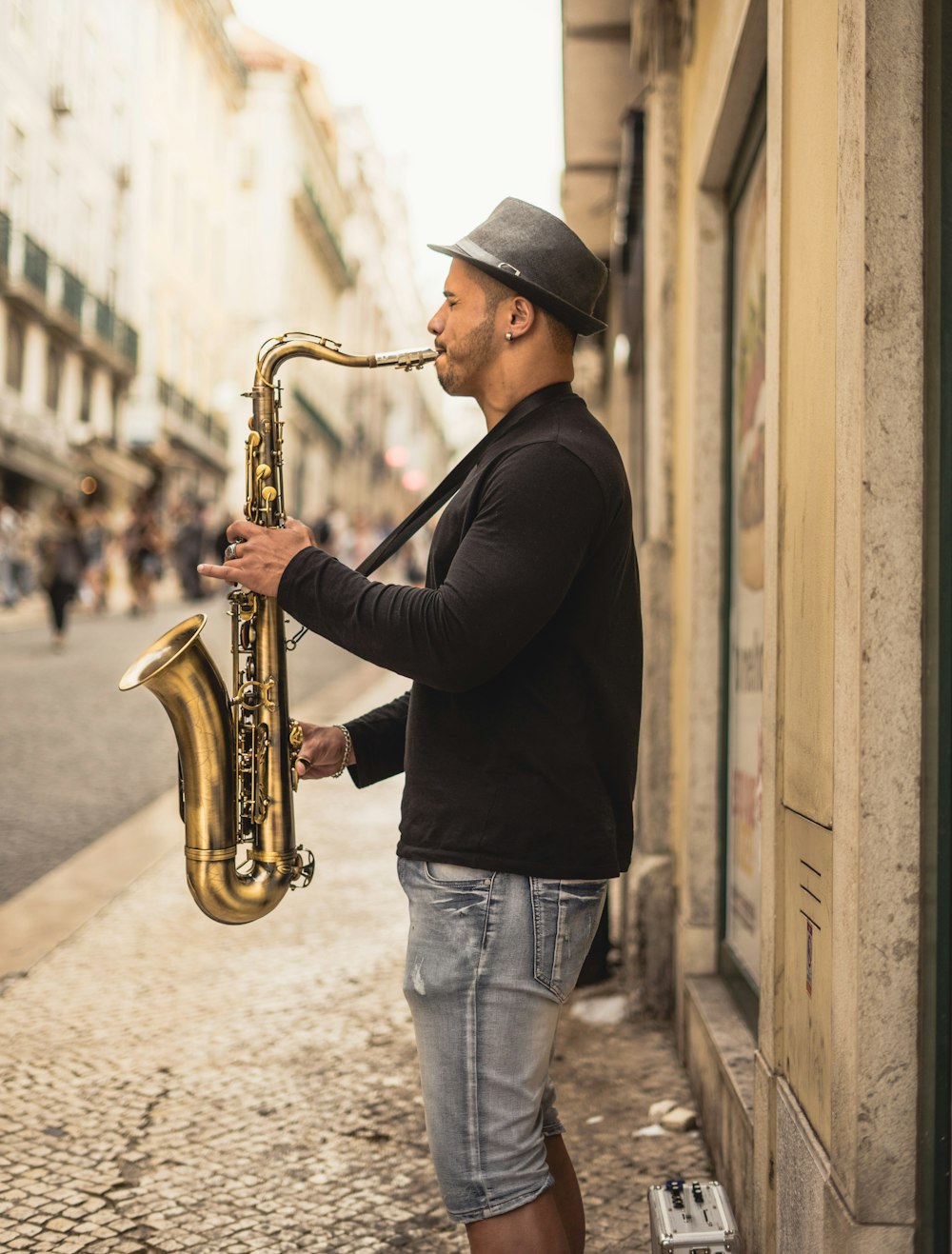 uomo che suona il sassofono color rame per strada durante il giorno