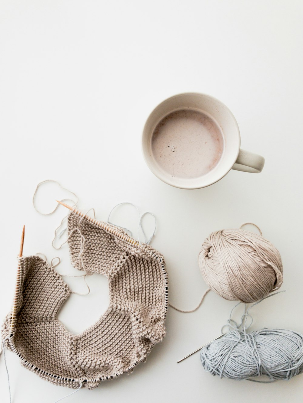 gray and blue yarns beside mug