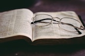 An open law book with a pair of glasses on top, representing legal knowledge and expertise.