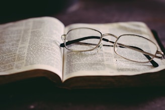 Close-up of an open book with a vintage pair of glasses resting on the pages