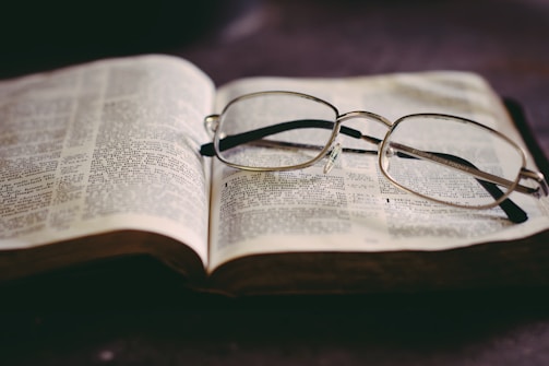 Open book with highlighted text and a pair of glasses resting on it.
