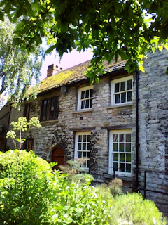 A cozy 14th-century stone cottage nestled within the medieval fort of Flaujac, bathed in soft morning light.