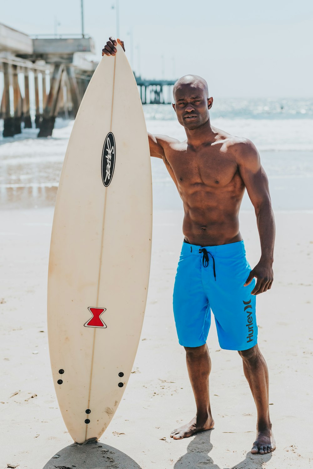 man standing beside white surfboard