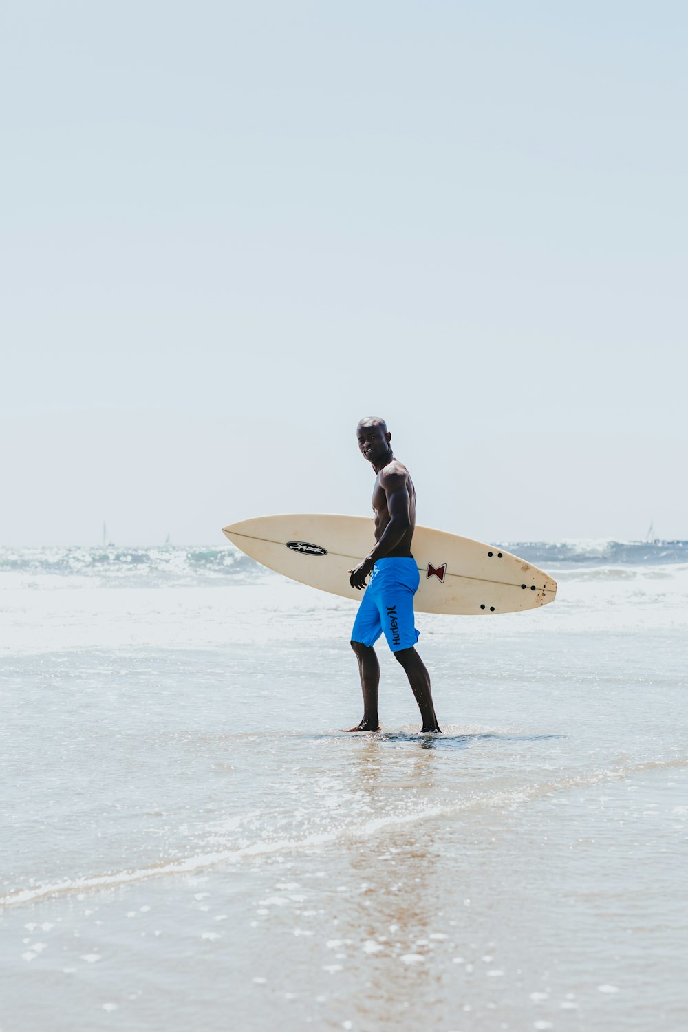 homme portant une planche de surf debout sur le rivage