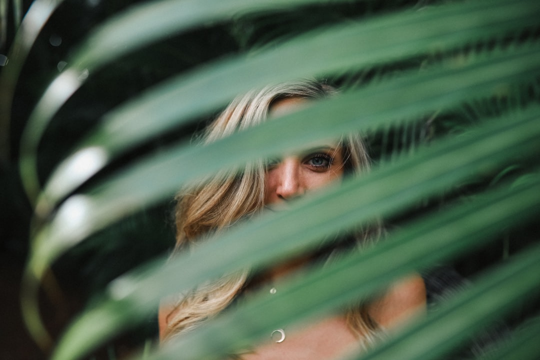 green leaf in front of smiling woman