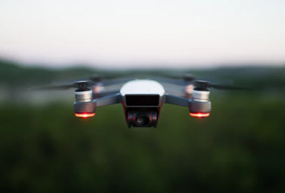 A sleek drone hovering over a suburban neighborhood at dusk, its camera focused and ready.