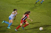 two women playing soccer on field