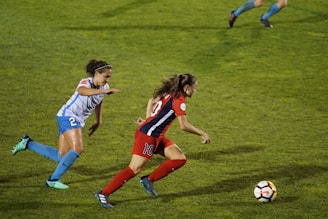 two women playing soccer on field