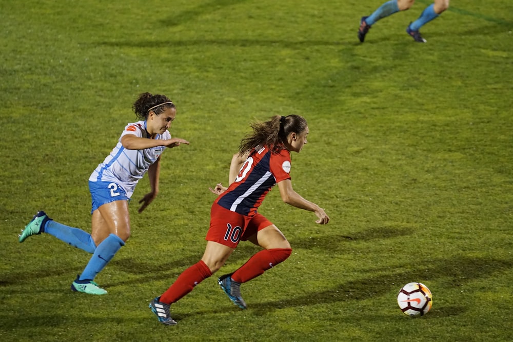 two women playing soccer on field