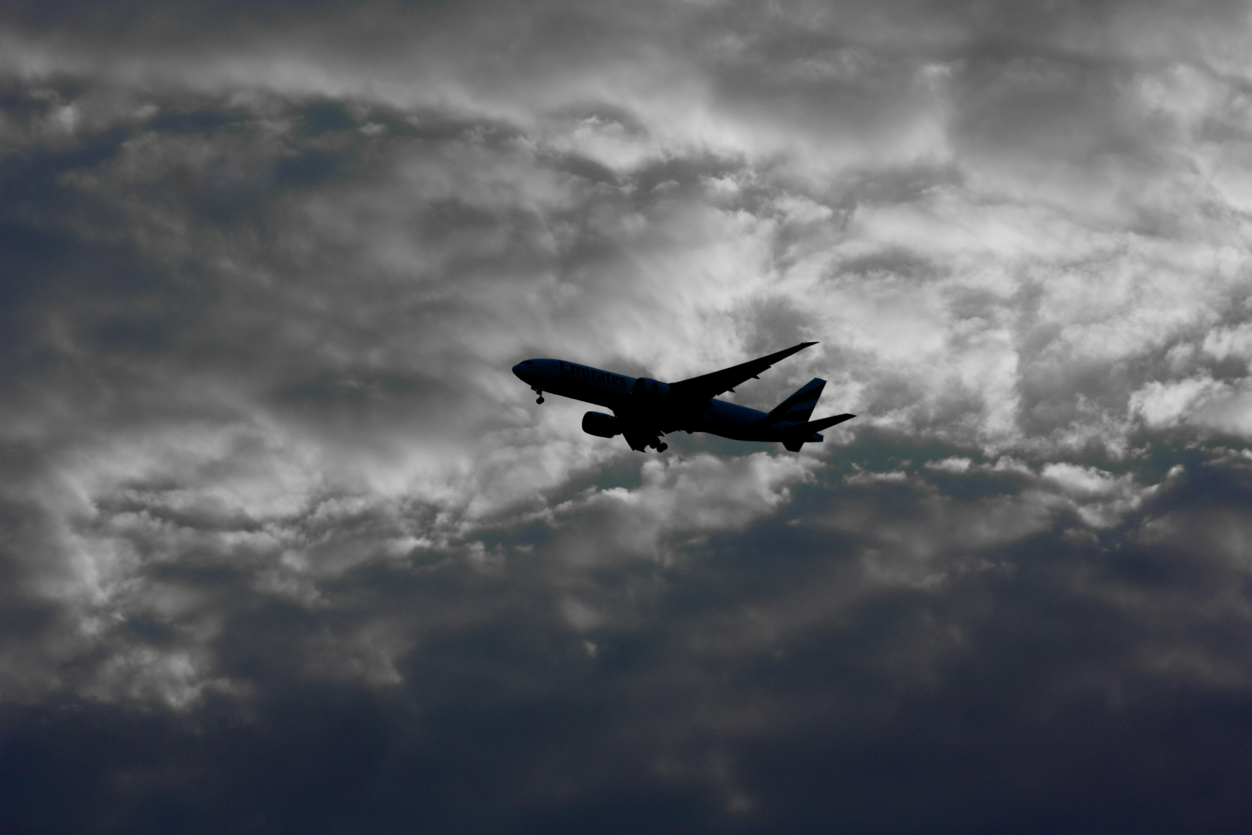 A380 superjumbo airliner in dark overcast sky, moody dramatic lighting, deep atmospheric shadows