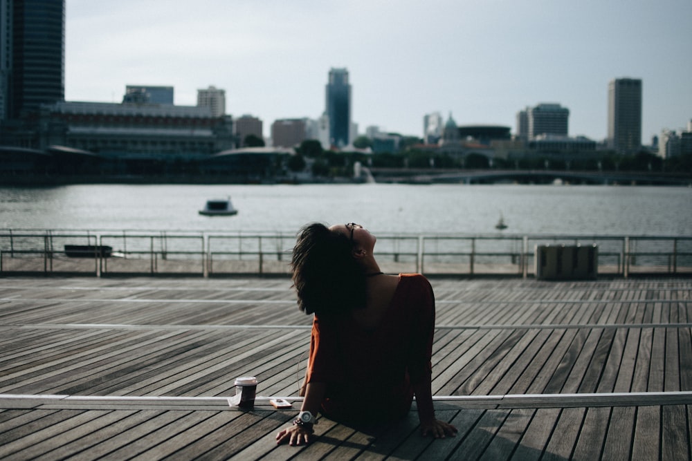 woman lying on wooden pallet near body of water during daytime