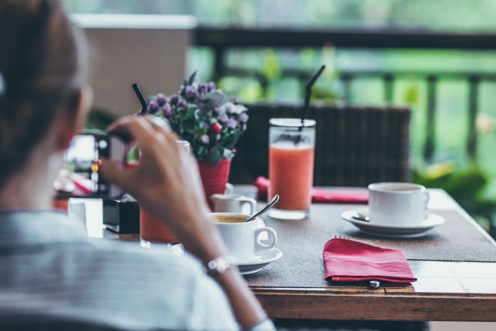 Photographie sélective de la boisson au jus de fraise sur la table à côté d’une tasse de thé