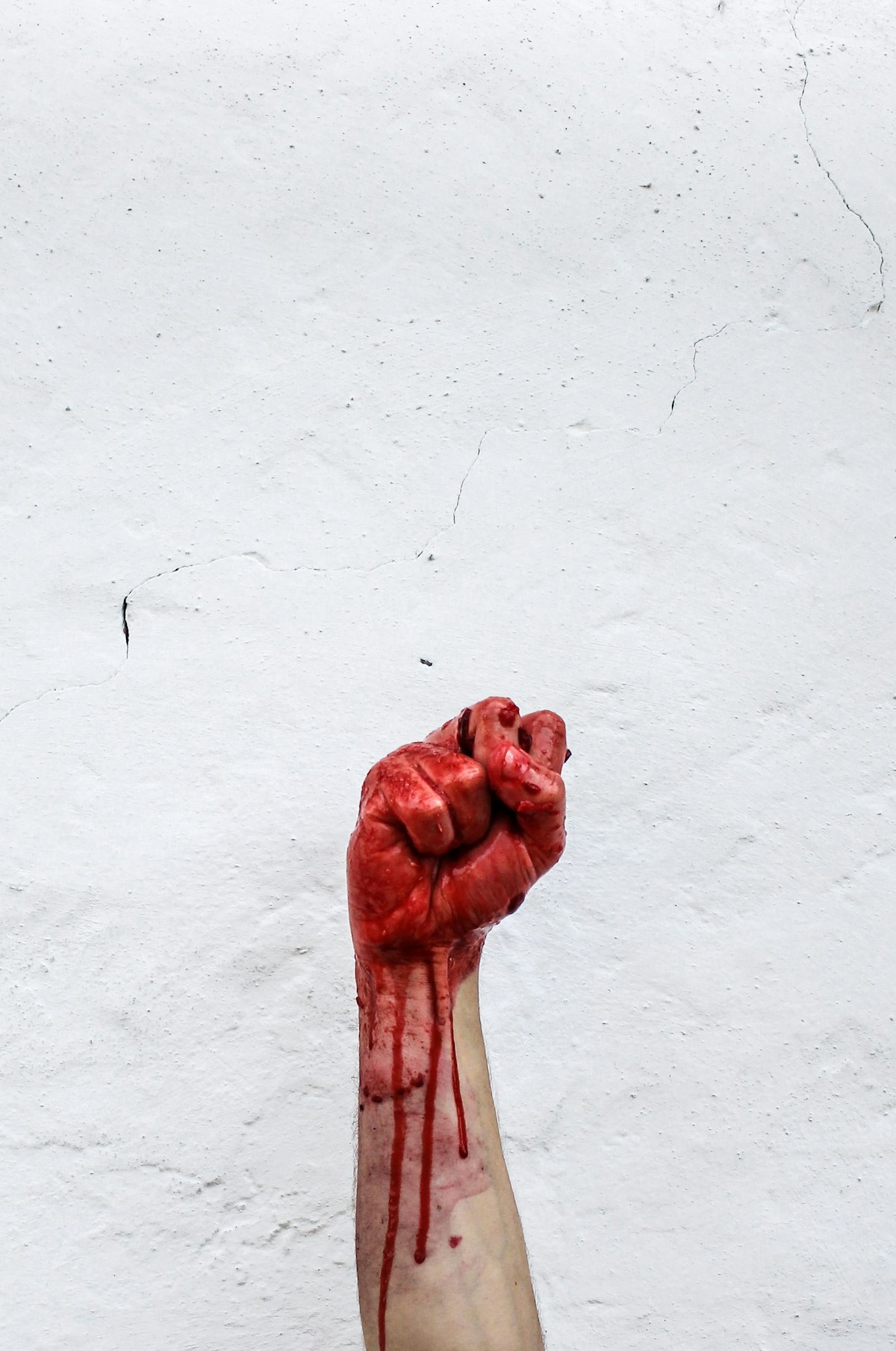 A bloody light skinned hand against a white wall.