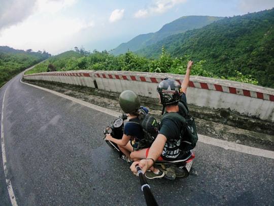 fish eye photography on woman riding motor scooter with man on bridge in Hải Vân Pass Vietnam