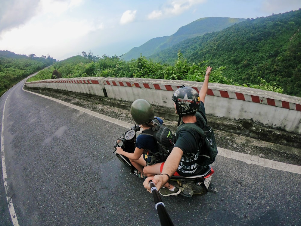 photographie d’œil de poisson sur une femme conduisant un scooter à moteur avec un homme sur le pont