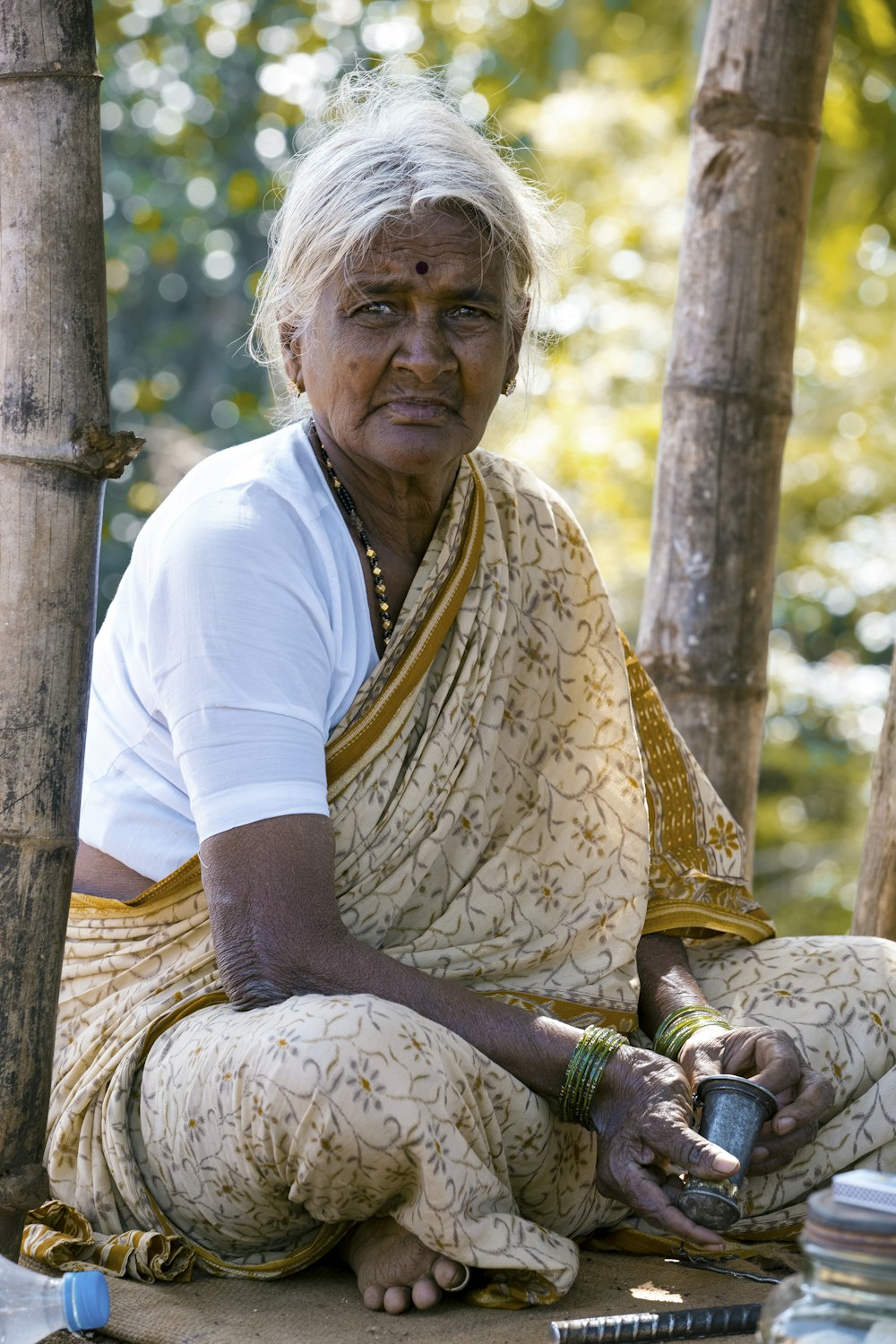 woman sitting beside bamboo tree wearing brown floral shawl