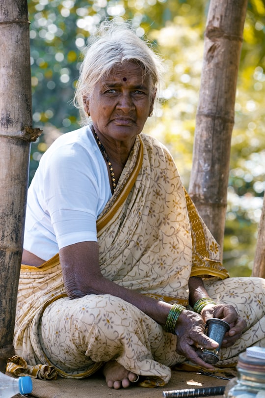 woman sitting beside bamboo tree wearing brown floral shawl in Bengaluru India
