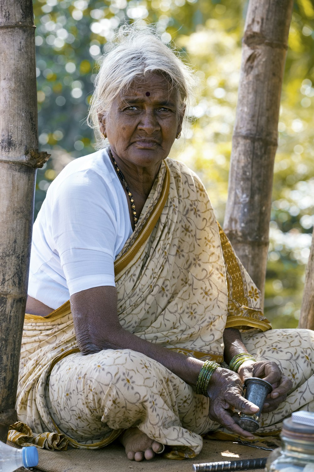 Frau sitzt neben Bambusbaum und trägt braunen Blumenschal