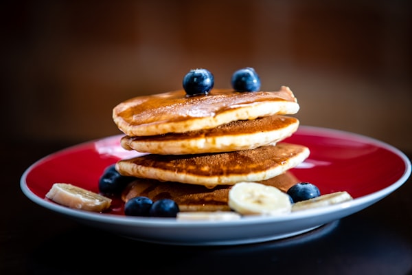 A plate for buttermilk pancakes, with a serving of blueberries and sliced bananas