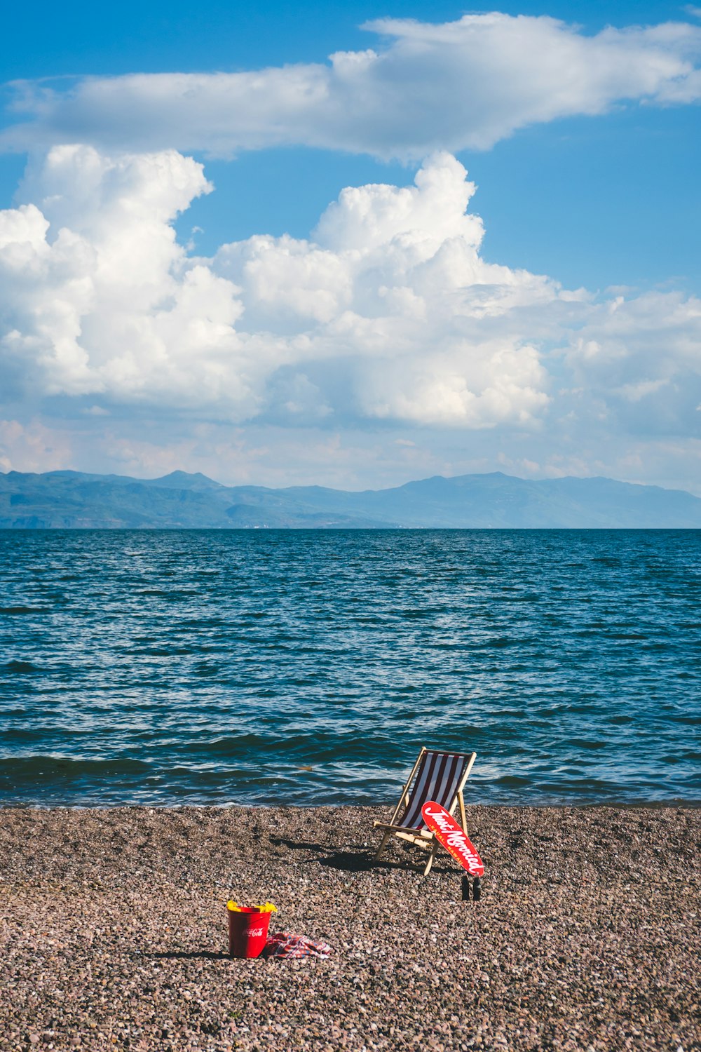 brown wooden camping chair near body of water