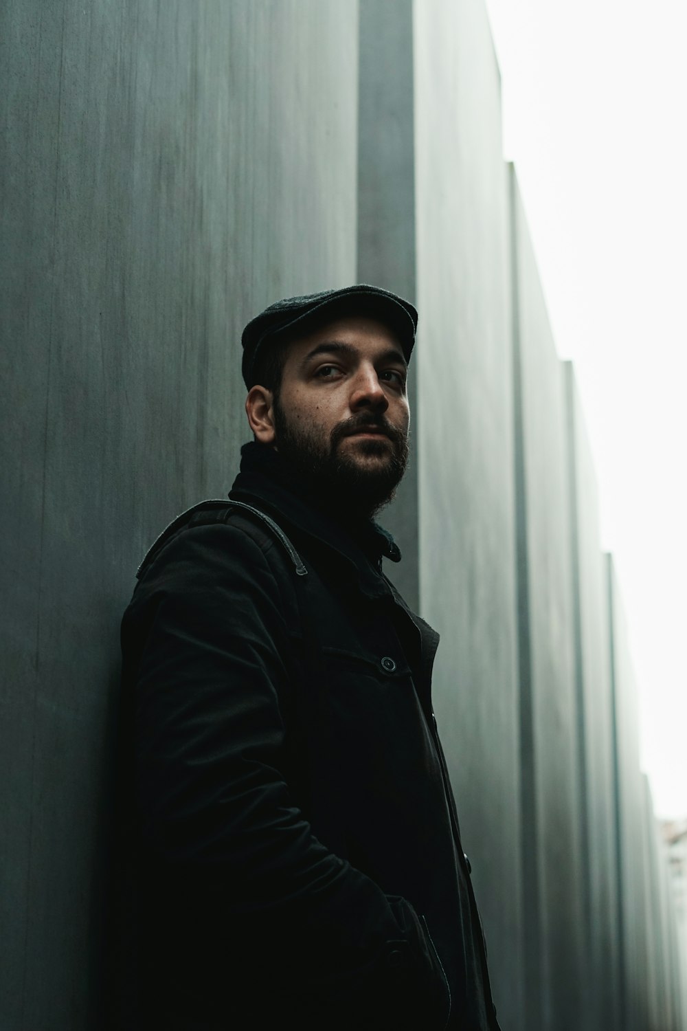 man leaning on white wall